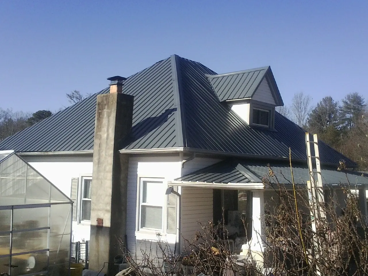 Dark blue standing seam metal roof on a white farmhouse with dormer — Slate & Tile Roof Repair by Roofing Brothers in Ironside