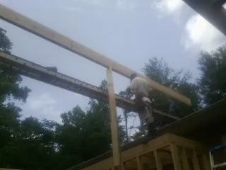 Carpenter setting a ridge beam over a new addition frame — Ice Dam Removal by Roofing Brothers in Ironside