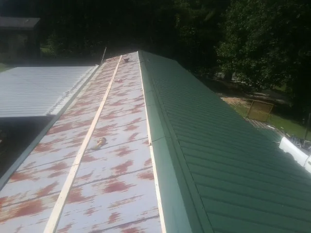 Old rusted panels beside newly installed green metal roofing — Wind Damage Roof Repair by Roofing Brothers in Ironside