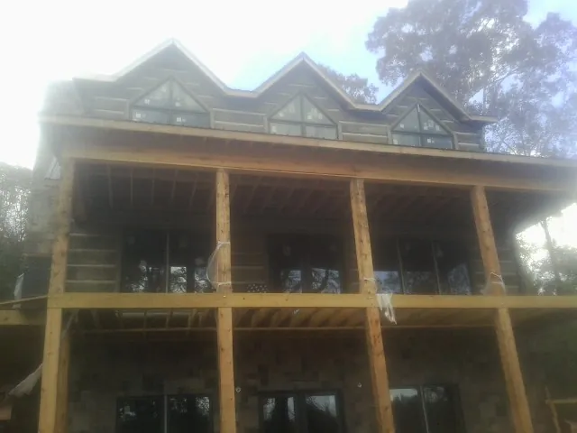 Dormers and porch framing on a large log home under construction — Roof Coating work by our crew in Ironside