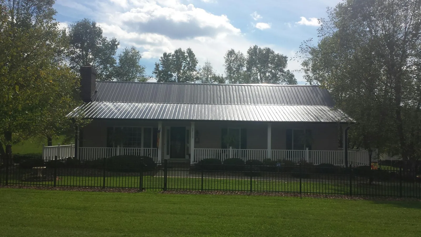 Gray metal roof on a brick ranch with a full width front porch — Gutter Guard Installation work by our crew in Ironside