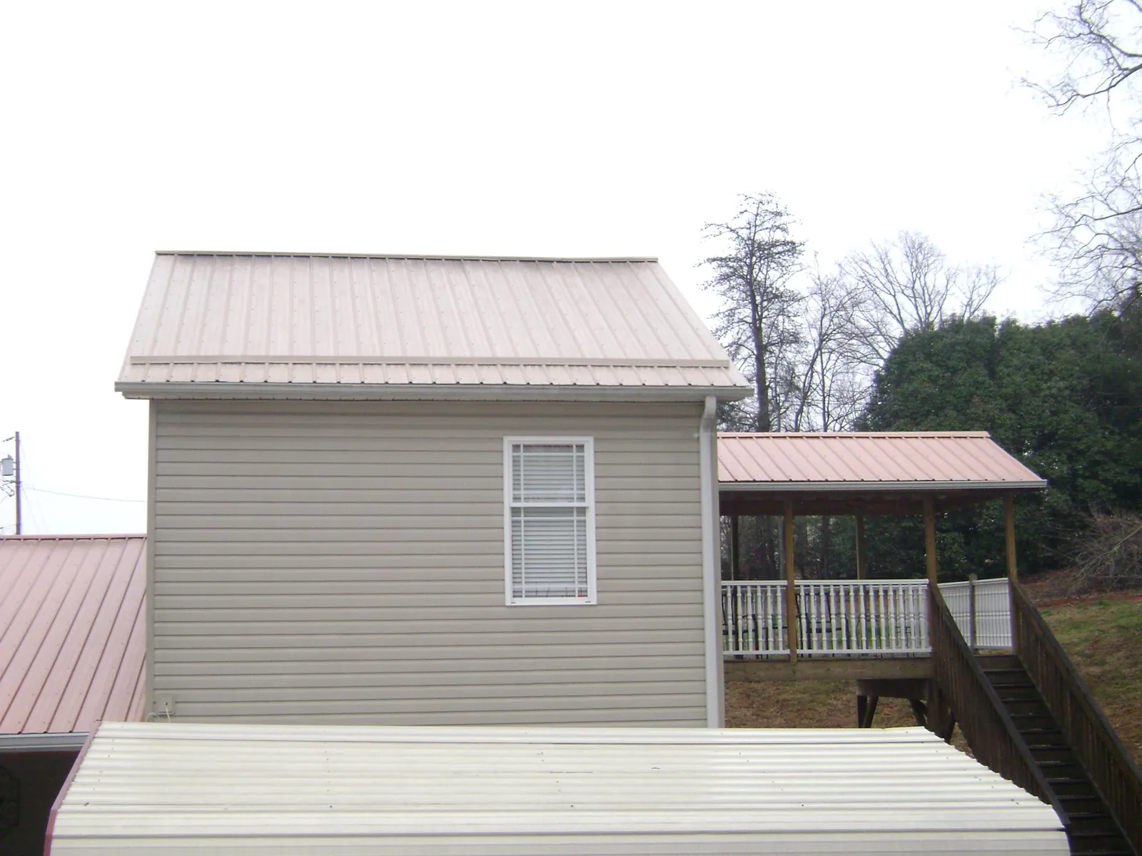 Tan metal roofs on a two story addition and attached porch, from a Roof Replacement job in Ironside