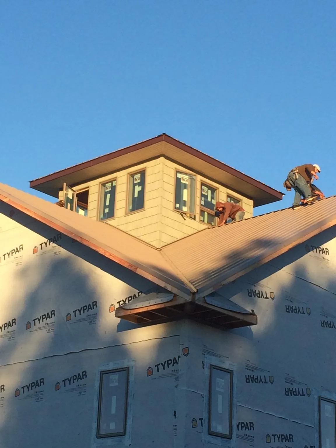Roofers working around a rooftop cupola on a new metal roof at sunset — Roof Waterproofing in Ironside by Roofing Brothers